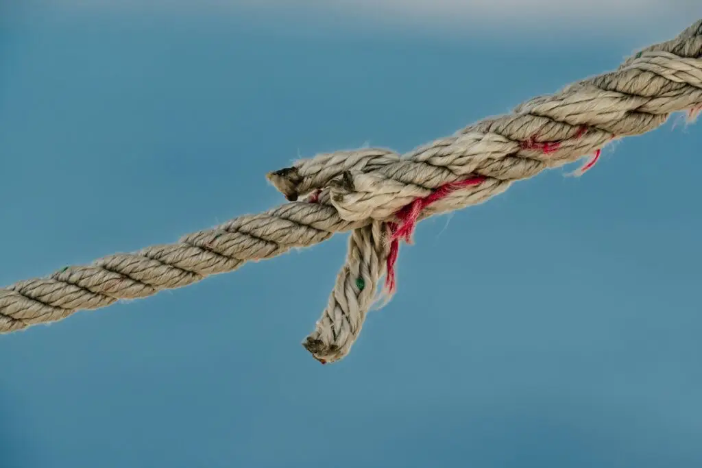 A detailed close-up photograph of a frayed nautical jute rope against a soft blue background.