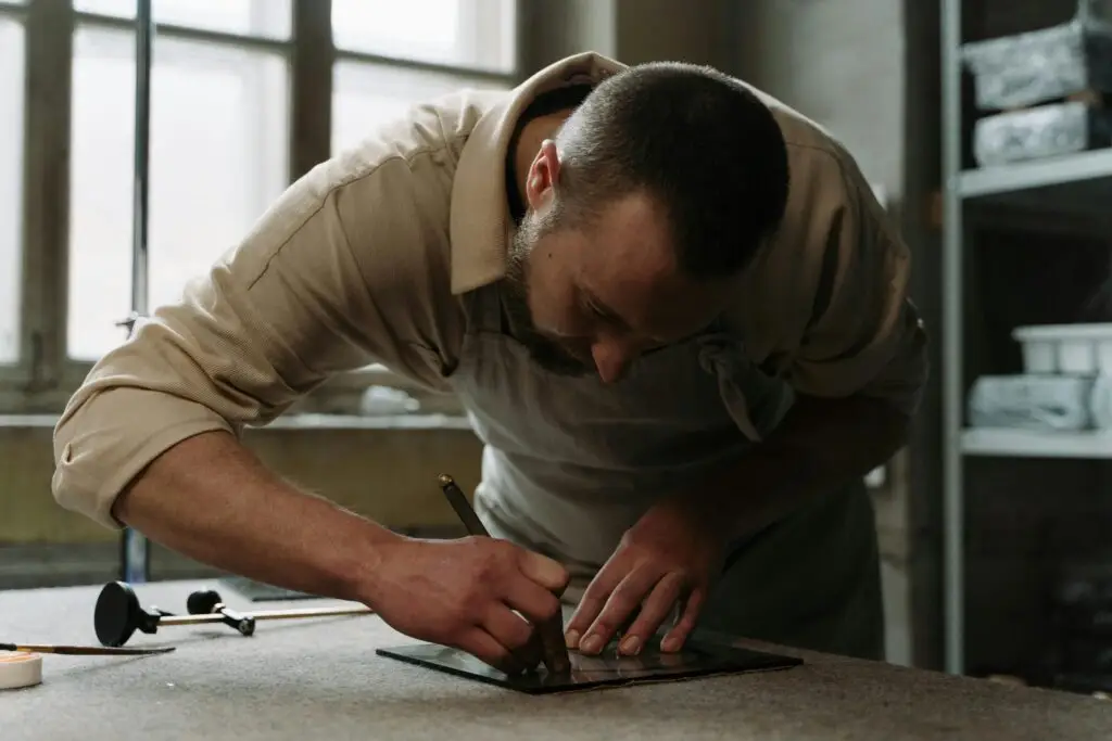 Artisan focuses on precise glass cutting technique in a well-lit workspace.